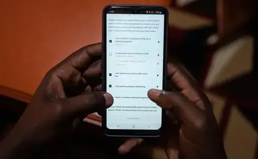Uber driver Emmanuel Bitok, one of more than 80 drives who spoke with NBC News, confirms the safety requirements on the Uber app before heading out for the day. Image by Nichole Sobecki/NBC News. Kenya, 2020.