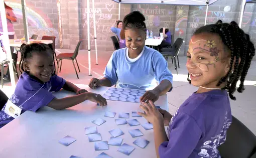 ALL SMILES Mi'Angel (left) and Mayal enjoy a card game with their mom, Donisha. Image by Jaime Joyce. United States, 2018.