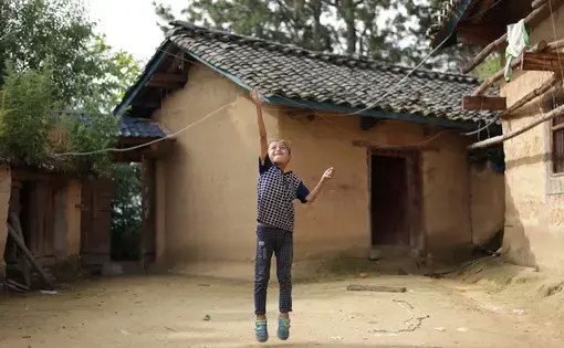 Eight-year-old Wang Jie jumps for the washing line in the courtyard of his family’s farmhouse in Liangshan Prefecture, Sichuan Province. Image by Max Duncan. China, 2016.