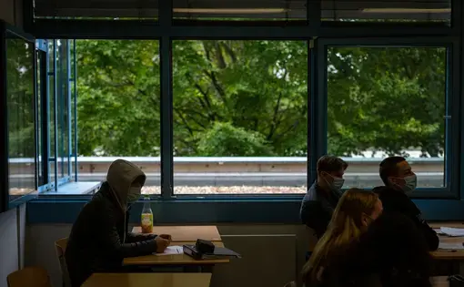 Students sit in a classroom with masks on and the windows wide up at a high school in Brühl, Germany, near Cologne. Image by Ryan Delaney. Germany, 2020.