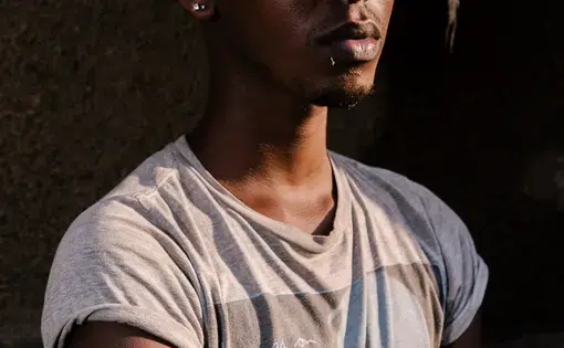 Javan, 19, a transgender woman, poses for a portrait near her mother's apartment in Kampala. She spent around eight months in Kenya as a refugee there after a mob beat her, stripped her naked and paraded her up and down the street yelling, "He's a homo," behind her near her Kampala home. Last summer, however, she returned to Uganda in order to make a stand. Image by Jake Naughton. Uganda, 2017.