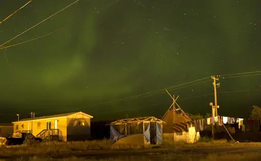 The northern lights fill the sky over the remote First Nations community of Attawapiskat. Attawapiskat is an isolated First Nation community located in northern Ontario, Canada, at the mouth of the Attawapiskat River on James Bay. On April 9, 2016, the community of approximately 2000 people declared a state of emergency after being overwhelmed with attempted suicides, over 100 attempts in a ten month period. Image by David Maurice Smith/Oculi. Canada, 2016.
