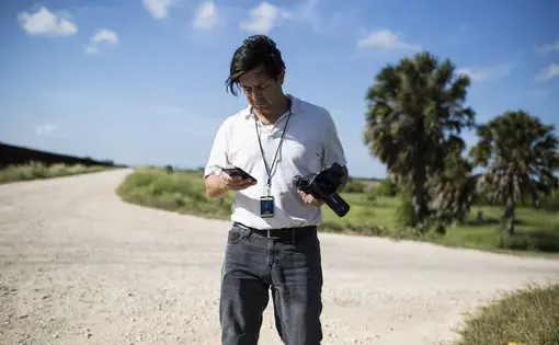 Julián Aguilar reporting near the border fence in Cameron County, Texas. Image by Martin do Nascimento. United States, 2017.