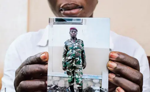 Marie-Yvette, photographed in Bangui on September 24, holds an undated picture of herself in her Séléka uniform. Image by Cassandra Vinograd. Central African Republic, 2017.