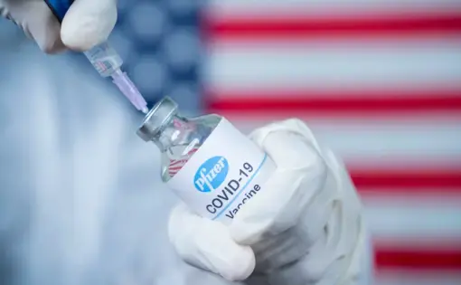 Doctor holding a Pfizer/Biontech vaccine. Image by lakshmiprasada S / Shutterstock. 2020.
