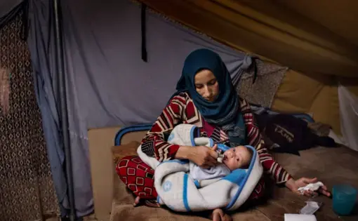 Illham holds her seven week-old baby Faraj in her tent on Nov. 20. Image by Lynsey Addario for TIME. Greece, 2016.
