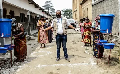 Christian, a Catholic Relief Services staff member, center, instructs aid beneficiaries in Kinshasa, Congo. Image by Justin Makangara/Catholic Relief Services. Democratic Republic of the Congo, undated.