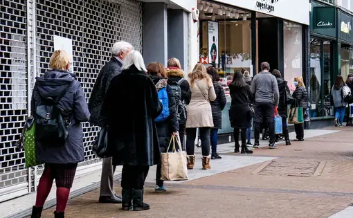 A line of people queuing to enter a shop on December 9 during COVID-19 Tier 2 restrictions in Kingston, London. Image by Richard M Lee / Shutterstock. United Kingdom, 2020.