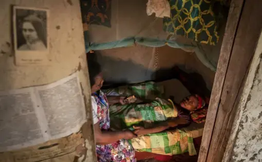 In this photo taken Tuesday, Nov. 5, 2019, palliative care nurse Madeleine Mukantagara, 56, left, prays with Vestine Uwizeyimana, 22, right, who has spinal degenerative disease and is taking oral liquid morphine for her pain, as she visits to check on her health at her home in the village of Bushekeli, near Kibogora, in western Rwanda. While people in rich countries are dying from overuse of prescription painkillers, people in Rwanda and other poor countries are suffering from a lack of them, but Rwanda…