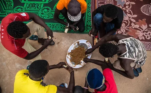 Migrants eat a meager meal of beans before making the dangerous trek into the Saharan desert and on to Libya. Image by Emily Kassie. Niger, 2016.
