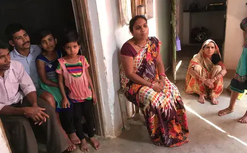 Pinki Sahu sits in a chair surrounded by family members. Pinki lost her sister, Sunita, when she died due to a botched sterilization procedure at a government-run camp in Chhattisgarh. Image by Hannah Harris Green. India, 2018.