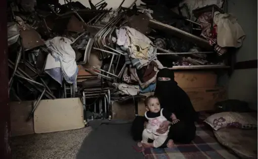 A woman sits with her baby inside a shelter for displaced persons in Ibb. Image by Nariman El-Mofty/AP Photo. Yemen, 2018.