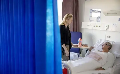 Dr. Jennifer Stevens, a pain specialist, talks with patient Cheryl Rowley who is awaiting surgery at St. Vincent's Hospital in Sydney, Australia, on July 17, 2019. "We were just pumping this stuff out into our local community, thinking that that had no consequences," says Stevens, a vocal advocate for changing opioid prescribing practices. "And now, of course, we realize that it does have huge consequences." Image by David Goldman. Australia, 2019.