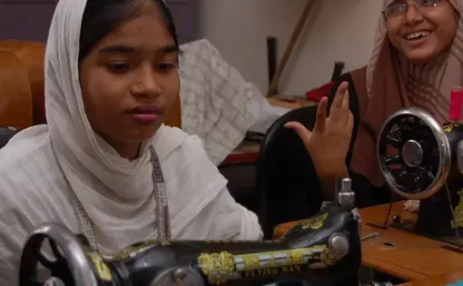 As Shompa shares her enthusiasm about the tailoring class, thirteen-year old Rozina concentrates on stitching her own dress. As she is deaf, it is hard to communicate with her. 1