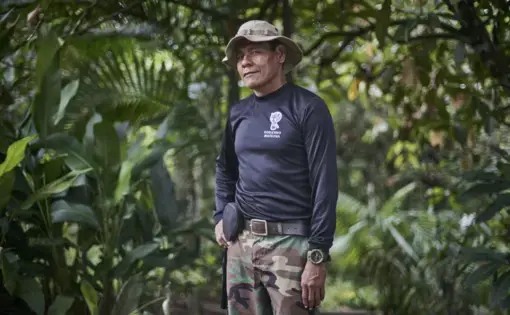 José Gregorio, leader of the Guardia Indígena Ambiental (Indigenous Environmental Guard), poses for a portrait. The photo shows a logo on the front of his shirt representing his organization, which protects the Amazon forest surrounding the Amacuyaco River. Image by Pablo Albarenga. Colombia, 2020.