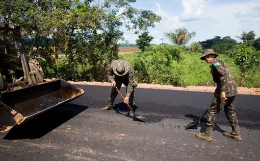 Soldiers pave some of the last miles of BR-163, a highway cutting through the Amazon basin which Bolsonaro had pledged to complete. For years, trucks carrying grain for export have lumbered along this slow, muddy road. Its completion significantly reduces transport time. Image by Heriberto Araújo. Brazil, 2019.