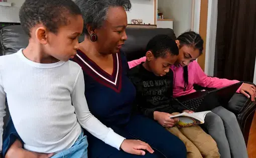 Regina Barrett, center, sits with her grandchildren Asa Barrett, left, 5, Hallie Barrett, 10, and Asher Barrett, 8, in her Monroe, NC home on Wednesday, February 10, 2021. Regina Barrett began juggling the roles of grandmother, caregiver and teacher to help out when the pandemic shutdown schools last year. Image by David T. Foster III. United States, 2021.