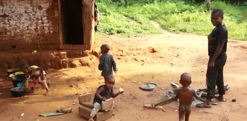 Four young children play outside while a woman watched over them.
