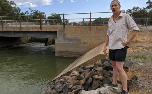 Farmer Carly Marriott stands by Australia's Mulwala Canal, which is considered the longest irrigation canal in the southern hemisphere. "It was a great engineering feat in its time," said Marriott. Image by Rae Ellen Bichell/MWNB. Australia, 2020.