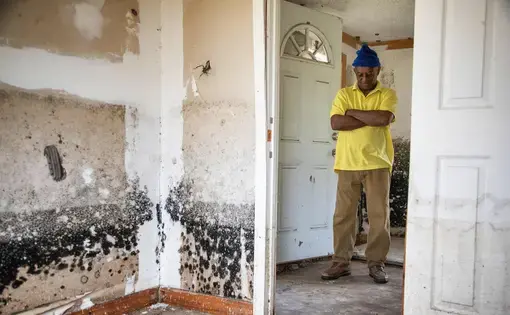 A man stands in the ruins of his house, destroyed by flood.