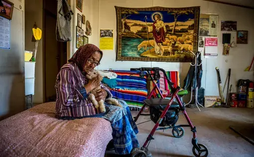 Helen Nez holding a lamb in her home in Blue Gap, Ariz. Image by Mary F. Calvert. United States, 2020.