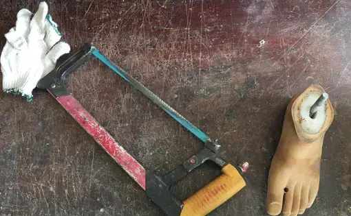 A prosthetic foot sits next to a saw.