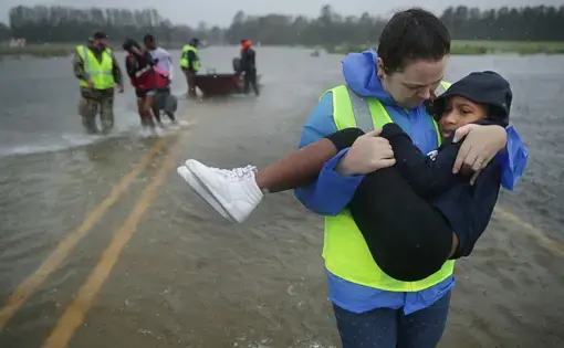 Volunteer Amber Hersel from the Civilian Crisis Response Team helps rescue 7-year-old Keiyana Cromartie and her family from their flooded home Sept. 14, 2018, in James City.