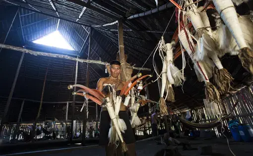 Un varón indígena alista un traje tradicional para realizar un ritual amazónico.