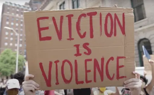 A protester holds a sign reading, "Eviction is violence"