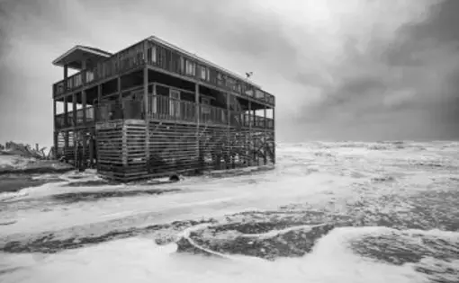 Surf washes around an Outer Banks home during a nor’easter in November 2019. Image by Jared Lloyd. United States, 2019.