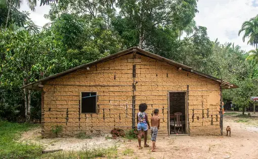 Duas pessoas e um cão à frente de uma casa na Comunidade Quilombola Abacatal, em Ananindeua, no Pará.