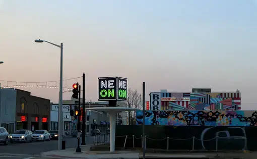 A neon sign reading "NEON" is lit up against the dusk sky.