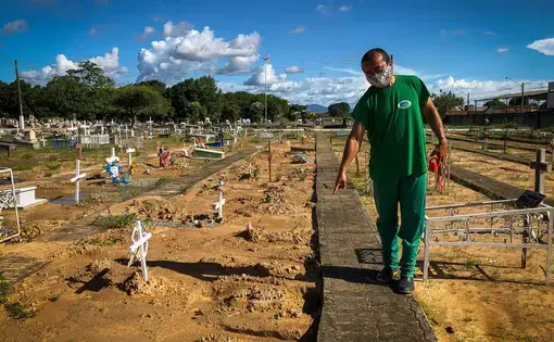 Um homem indica o tumulo do filho de Lucita Sanoma num cemitério.