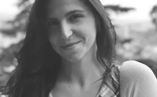 A black and white headshot of Mariana Palau, smiling at the camera wearing a plaid shirt.