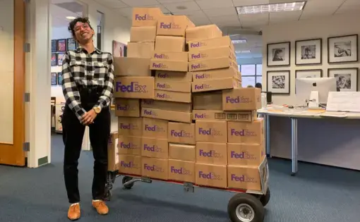 An intern stands with a pallet of 1619 magazine copies to be shipped to schools.