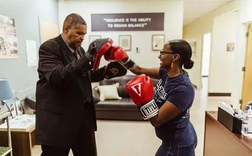 Gregory Banks—a torture survivor and CTJC Learning Fellow—boxes with a former intern, Helina Haile. Banks and Haile worked on launching a community healing boxing program at the Chicago Torture Justice Center.