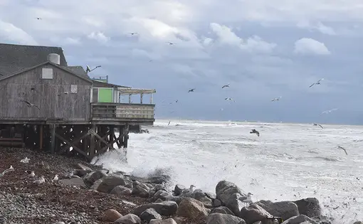 Waves at the beach hitting rocks on the shore.