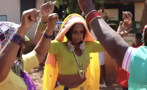 Women dance with their arms raised.