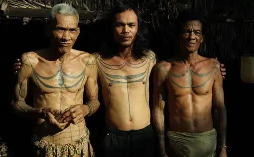 Tiga pria menunjukkan tato khas Mentawai pada tubuh mereka.