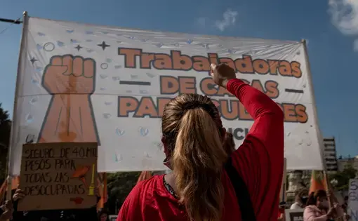 A person stands, with their arm raised and back to the camera, in front of a banner.