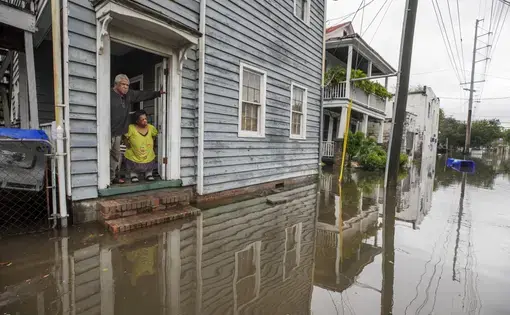 A man and woman look at flooding outside a home in Charleston, South Carolina.