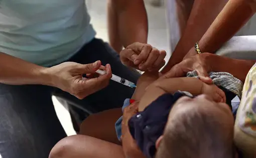 Health worker injecting vaccine to child.