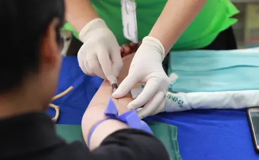 A medical worker administers a shot into the arm of a patient.