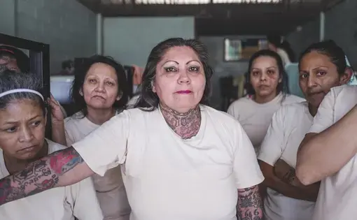 women stand in white tee shirts in a prison