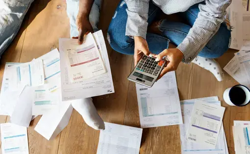 photo of someone sitting on floor calculating bills