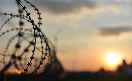 barbed wire at a prison at sunset.