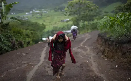 young girl carrying wood on her back