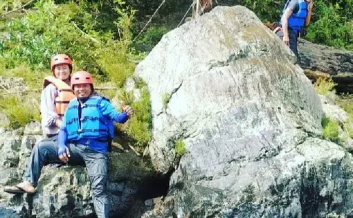 Wisatawan arung jeram saat berpose di samping fosil pohon Araucarioxylon di area Geopark Merangin di Desa Air Batu. Menurut para ahli geologi, fosil pohon ini berumur 300 juta tahun atau periode permian. (Liputan6.com/dok Air Batu River)