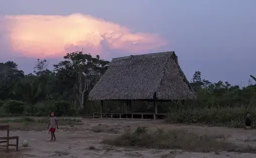 Two children play football as the sun sets.