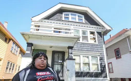 Woman stands in front of house